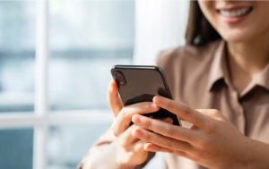 A smiling social media manager creating digital content on her mobile phone