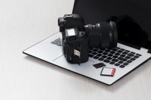 A videographer's camera on top of a laptop on a desk